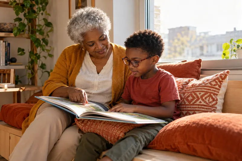 A grandmother and young boy arrange a comfortable window-seat reading nook.